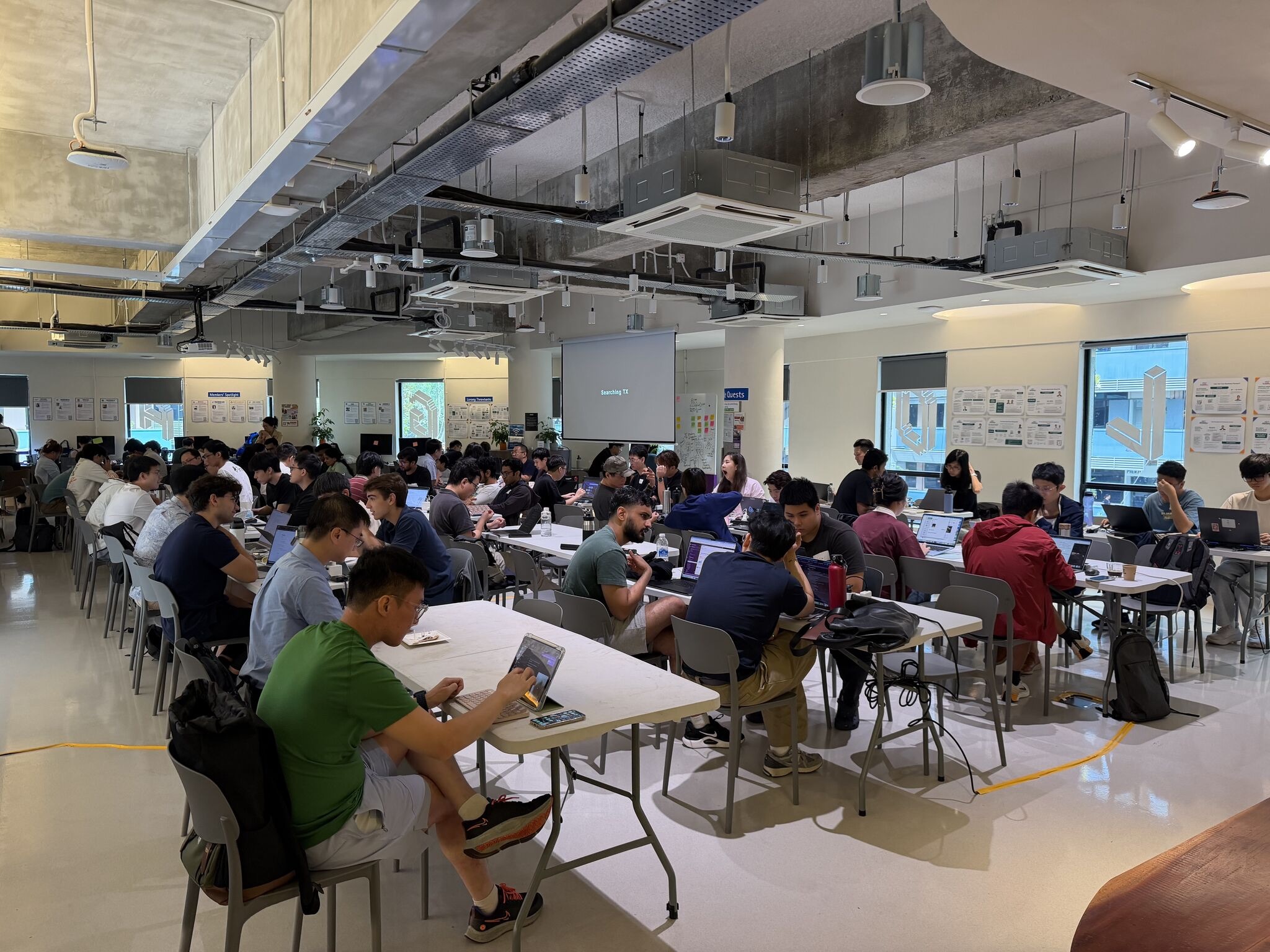 Groups of builders collaborating on laptops around a shared workspace