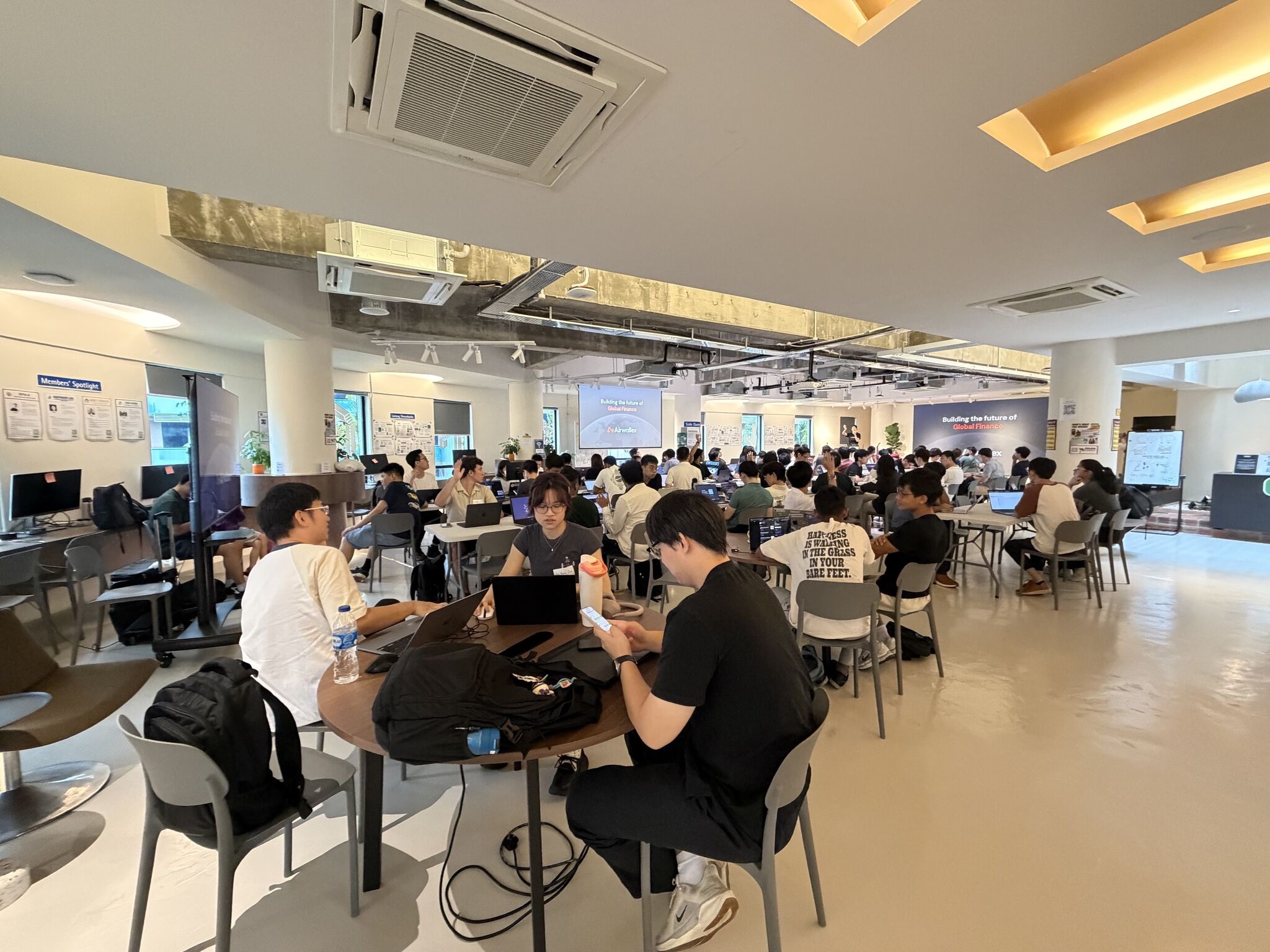 Builders working together on laptops at shared tables during a previous community session
